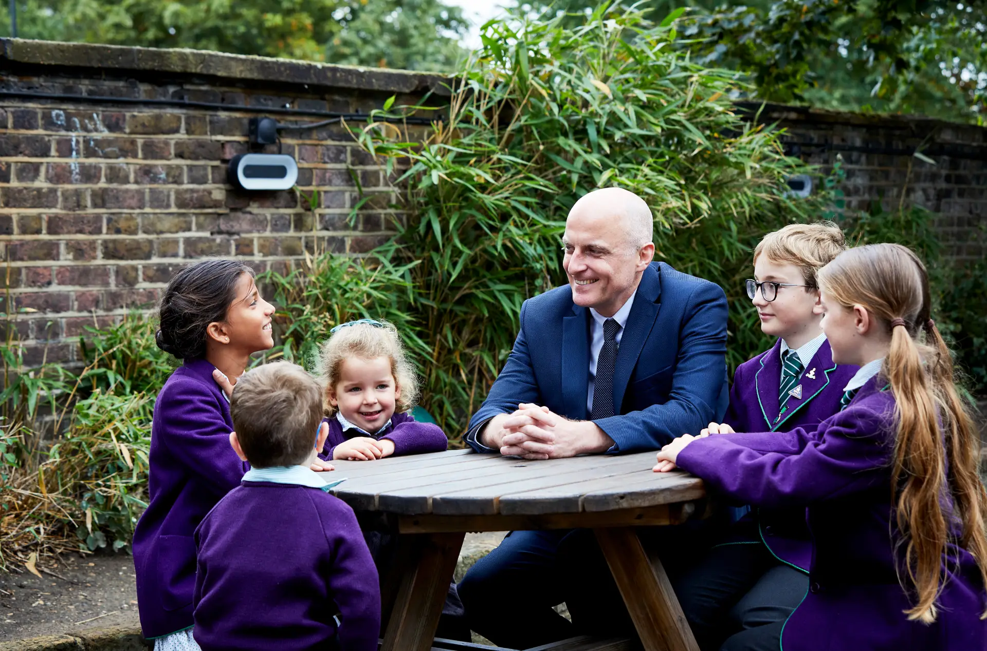 Headteacher sitting outside with pupils talking
